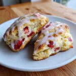 Two halves of freshly baked Strawberry Cream Scones with Vanilla Glaze resting on a white plate.