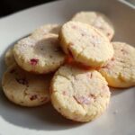 A close-up stack of round Strawberry Lemon Shortbread Cookies topped with coarse sugar crystals.
