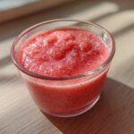 Close-up of blended strawberries, likely the base for the Strawberry Miso Vinaigrette, in a small clear glass.