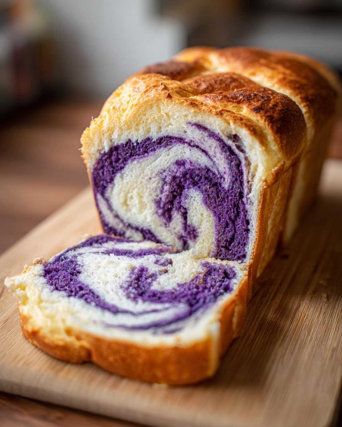 A loaf of freshly baked Ube Coconut Swirl Bread, sliced to show the vibrant purple ube and white coconut swirl pattern.
