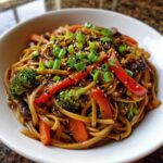 Close-up of Udon Stir-Fry with Sesame Vegetables, featuring thick noodles, red peppers, broccoli, and green onions.